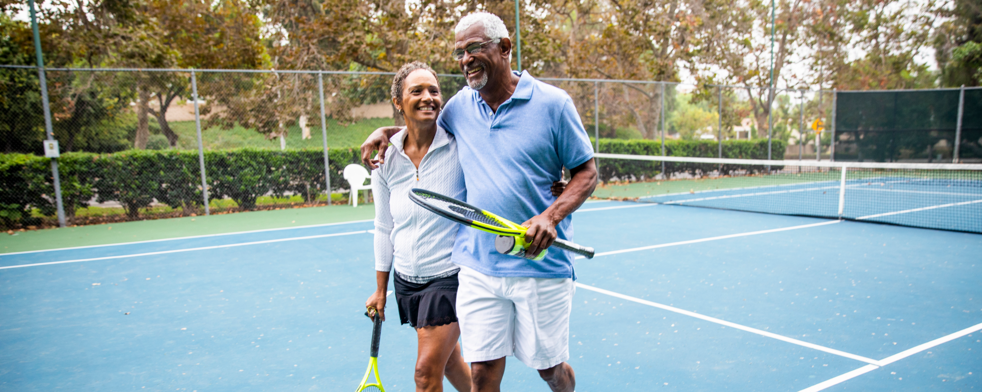 Man and a women smiling leaving a game of tennis together