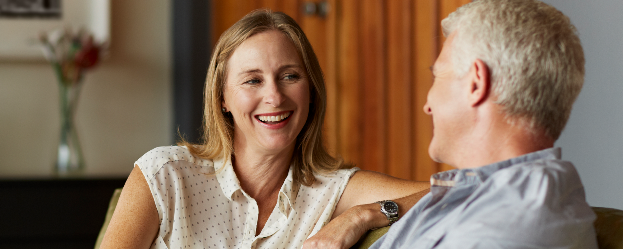 Man and a woman on a couch smiling in their living room
