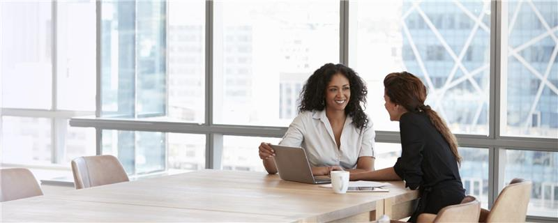 Women sitting at a desk in an office on the computer.