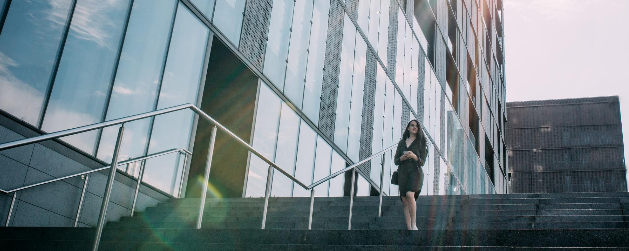 Woman walking down steps near office building.