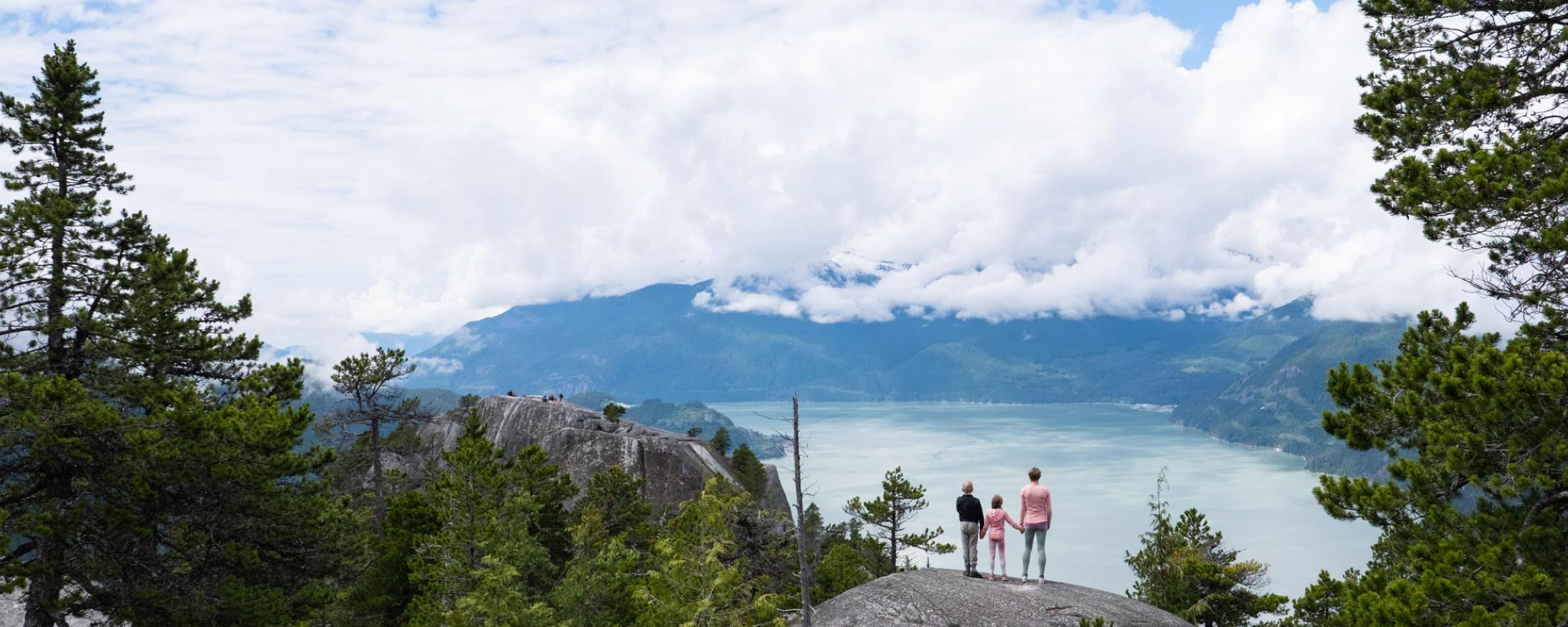 Parent and child at cliff overlooking landscape.
