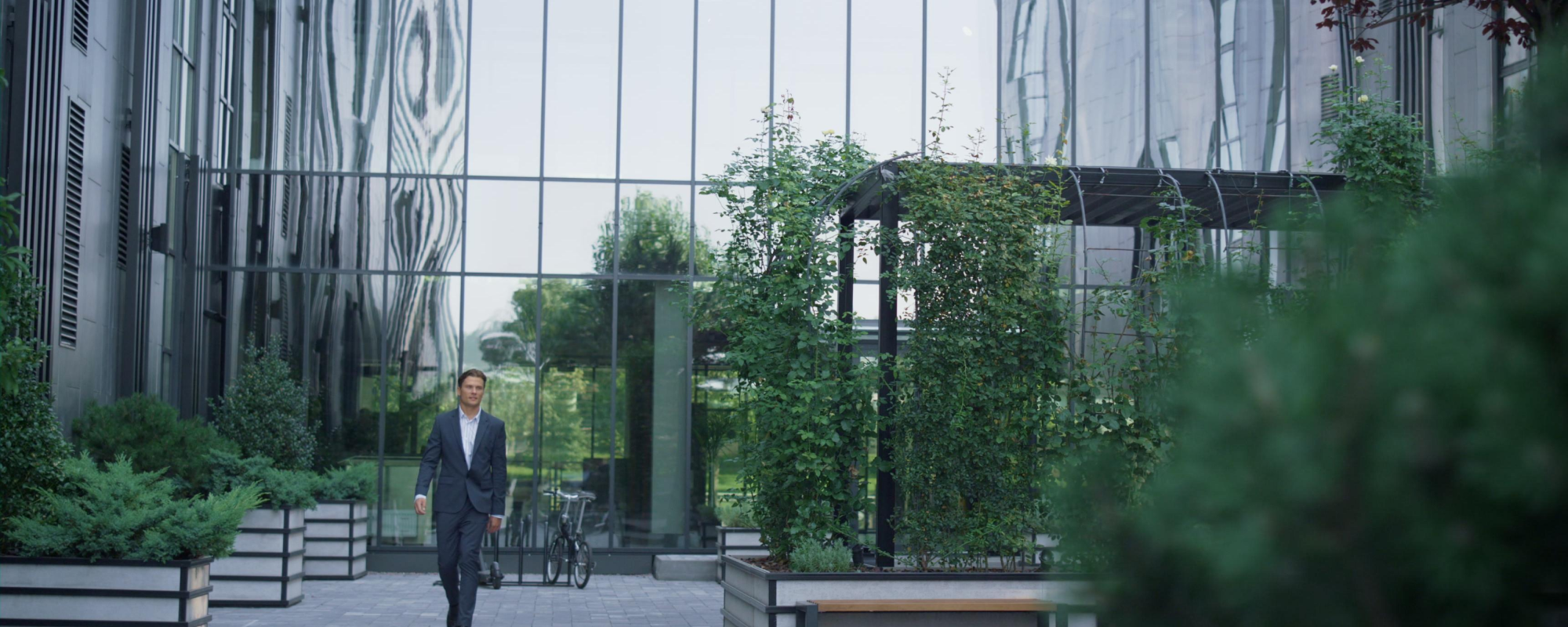 Man walking in front of office building with trees in background.
