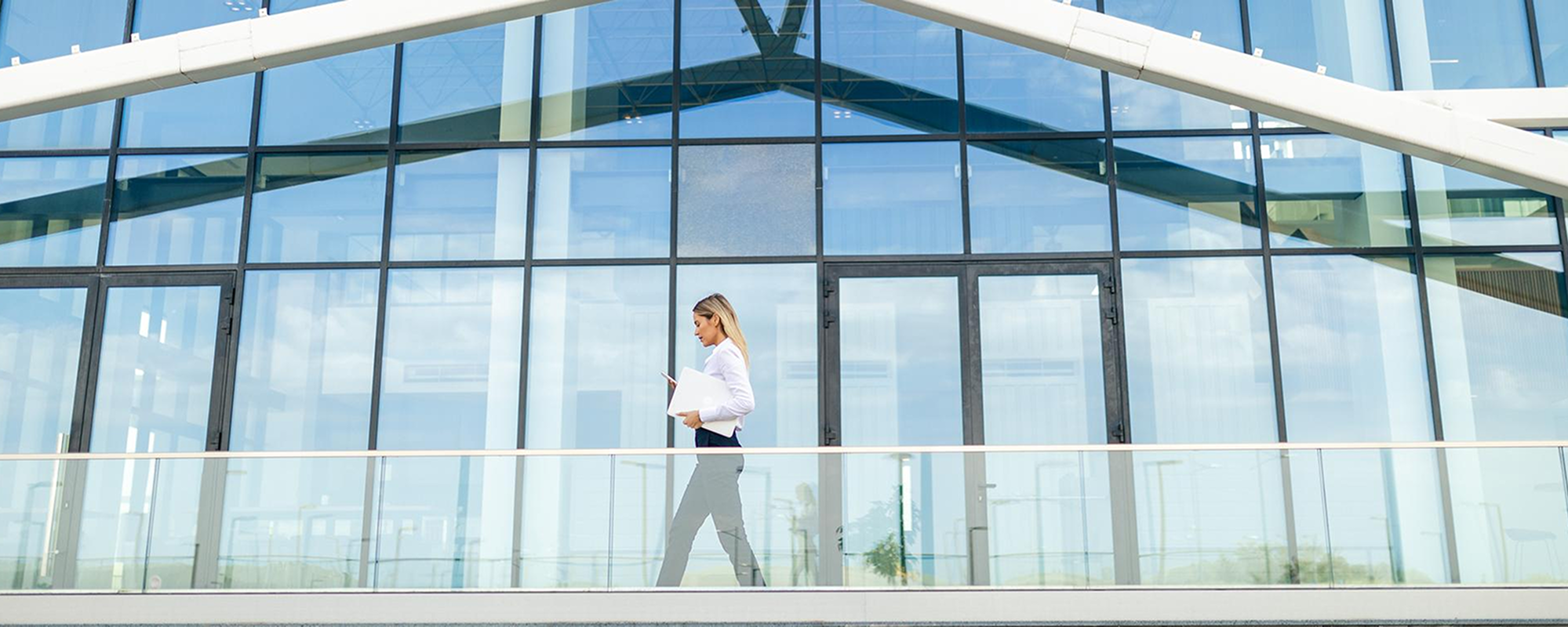 Woman walking in front of modern office building.