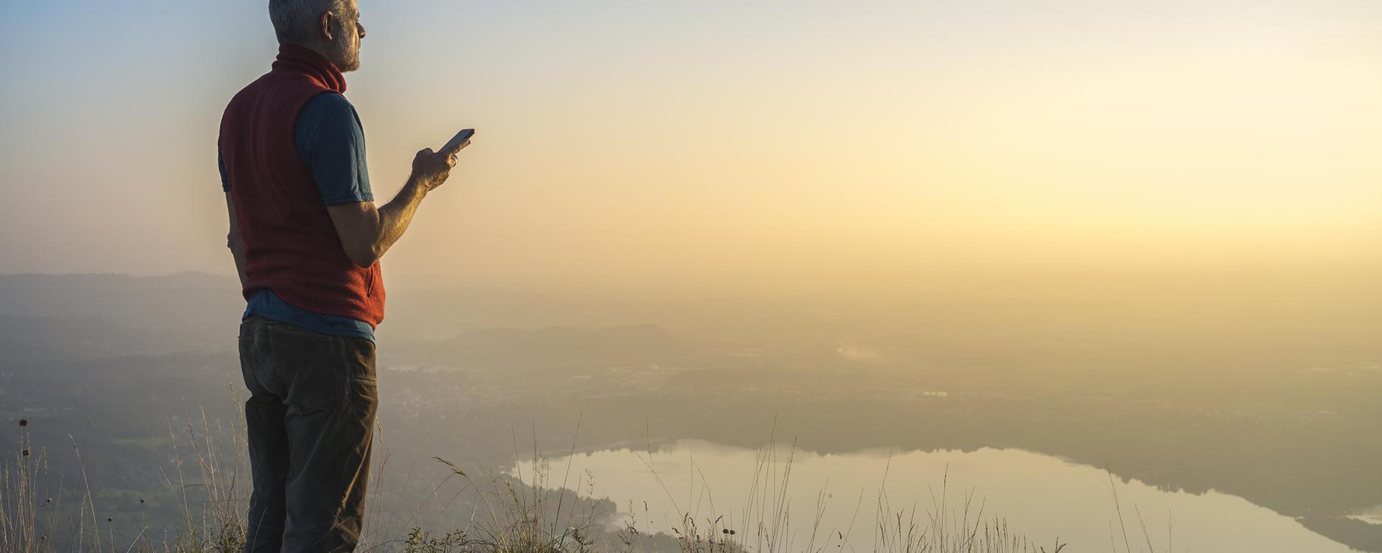 Person standing on top of a hill on phone.