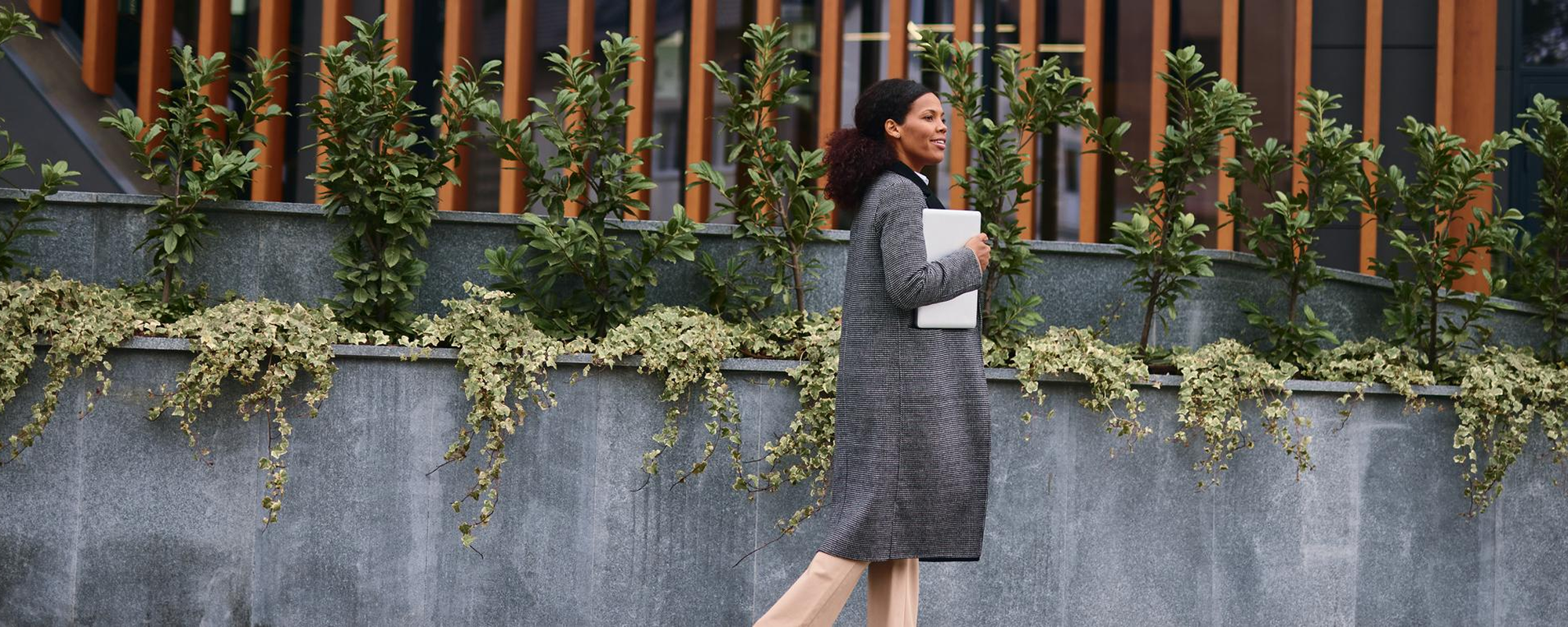 Woman walking in front of building with papers in her arm